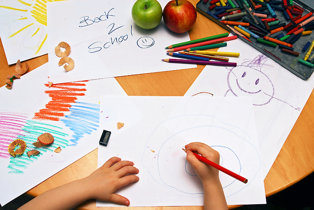 Little hands drawing between school supplies and apples